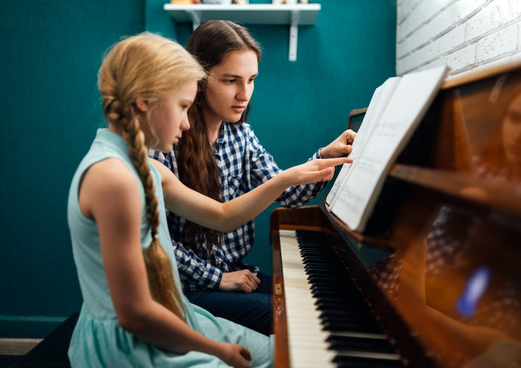 Piano teacher giving a music lesson to her student